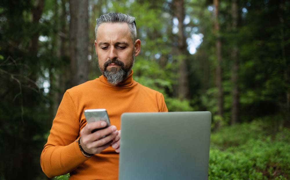 Man med laptop i skogen