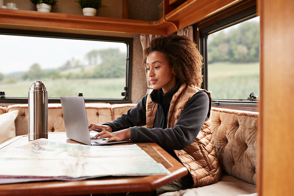 Woman sits in front of a laptop in her caravan