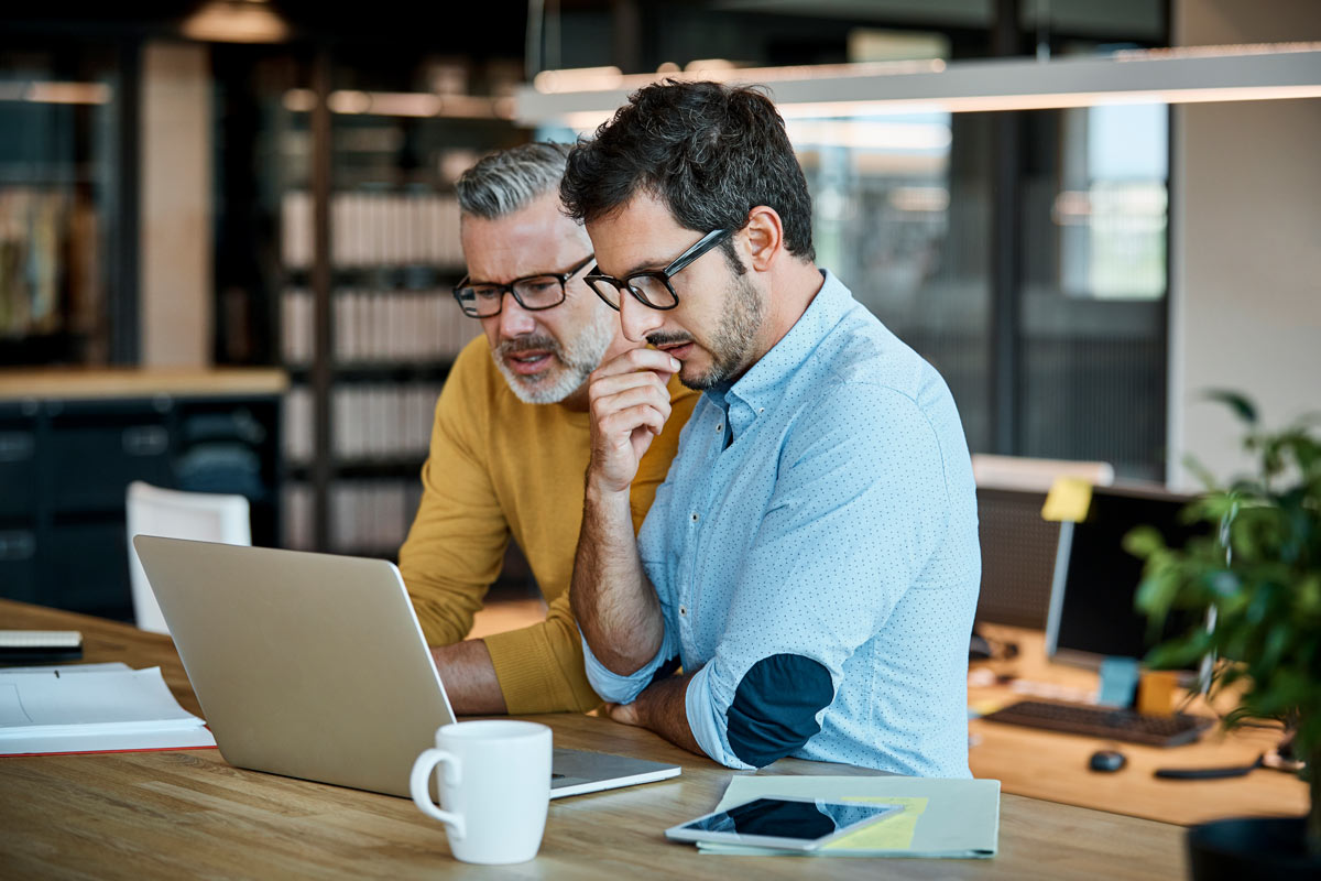 
Two employees stand in front of a laptop